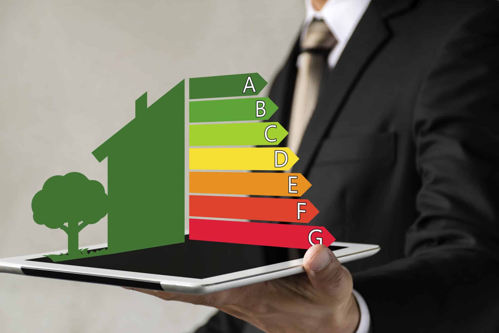 A businessman holds a digital tablet, reviewing house efficiency ratings and energy audits.