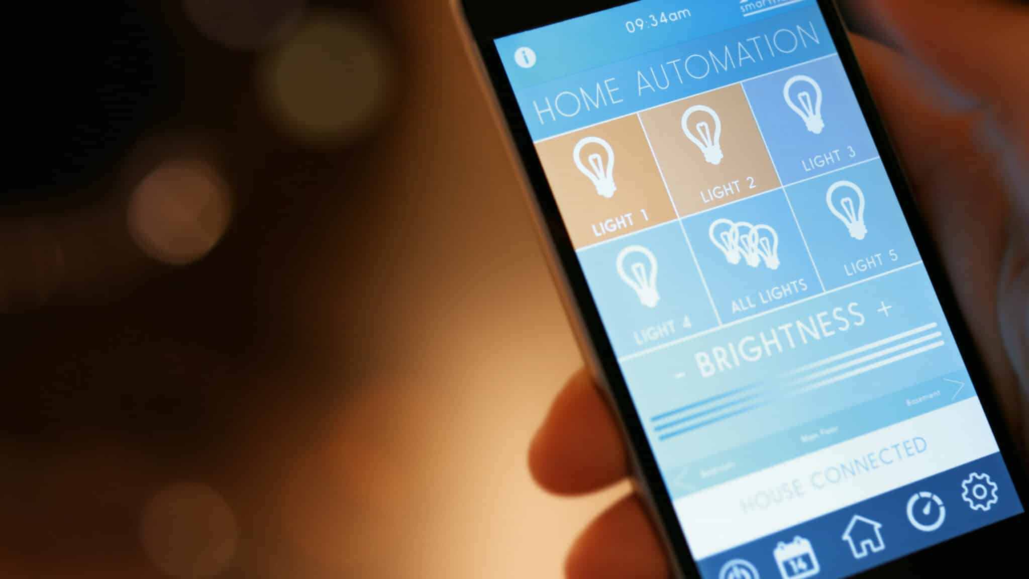 A man uses his smartphone with a home automation smart lighting control app to turn on the lights in his house.